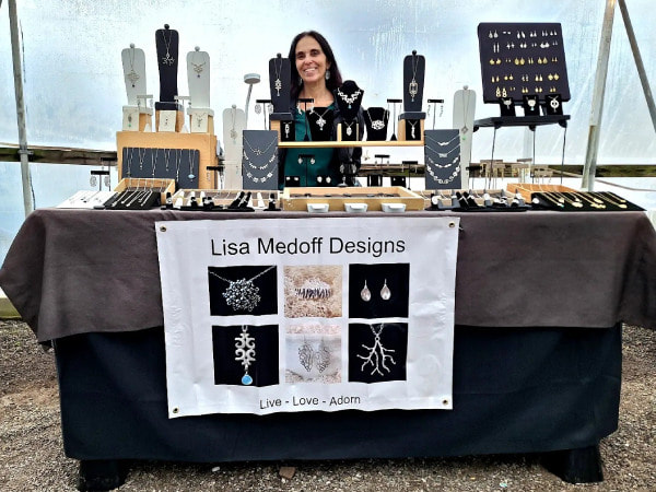 Lisa Medoff standing behind a large jewelry display